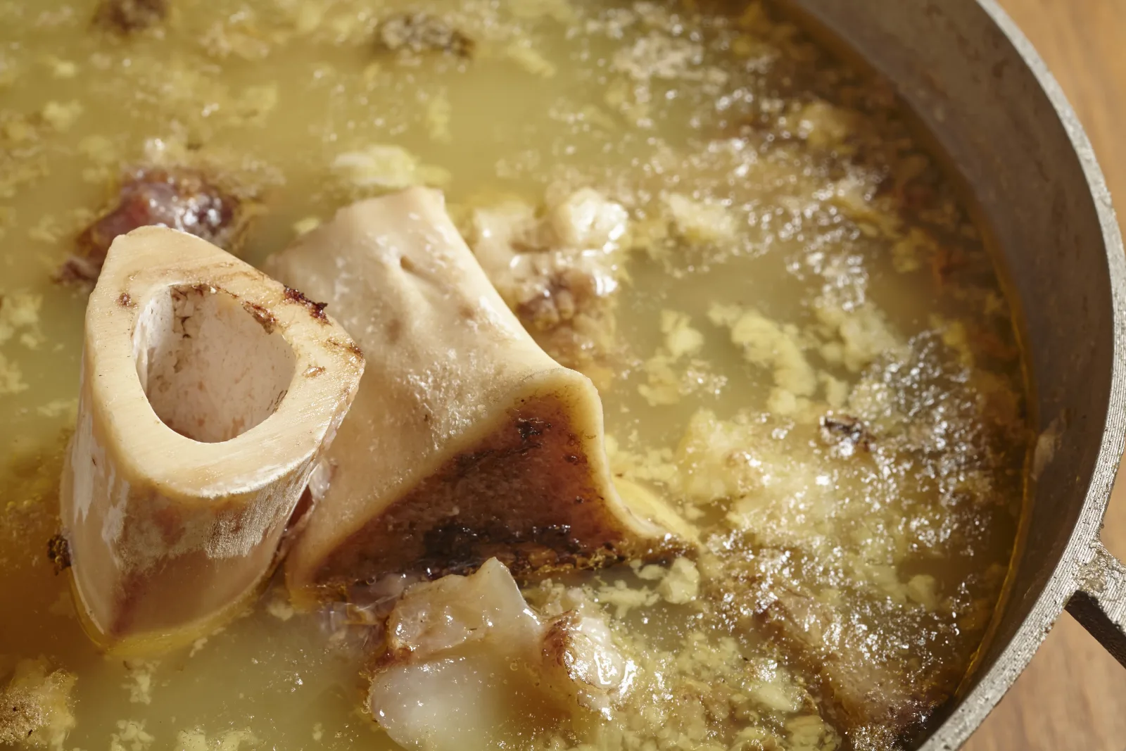 Bone broth simmering in a pot with a marrow bone and connective tissue