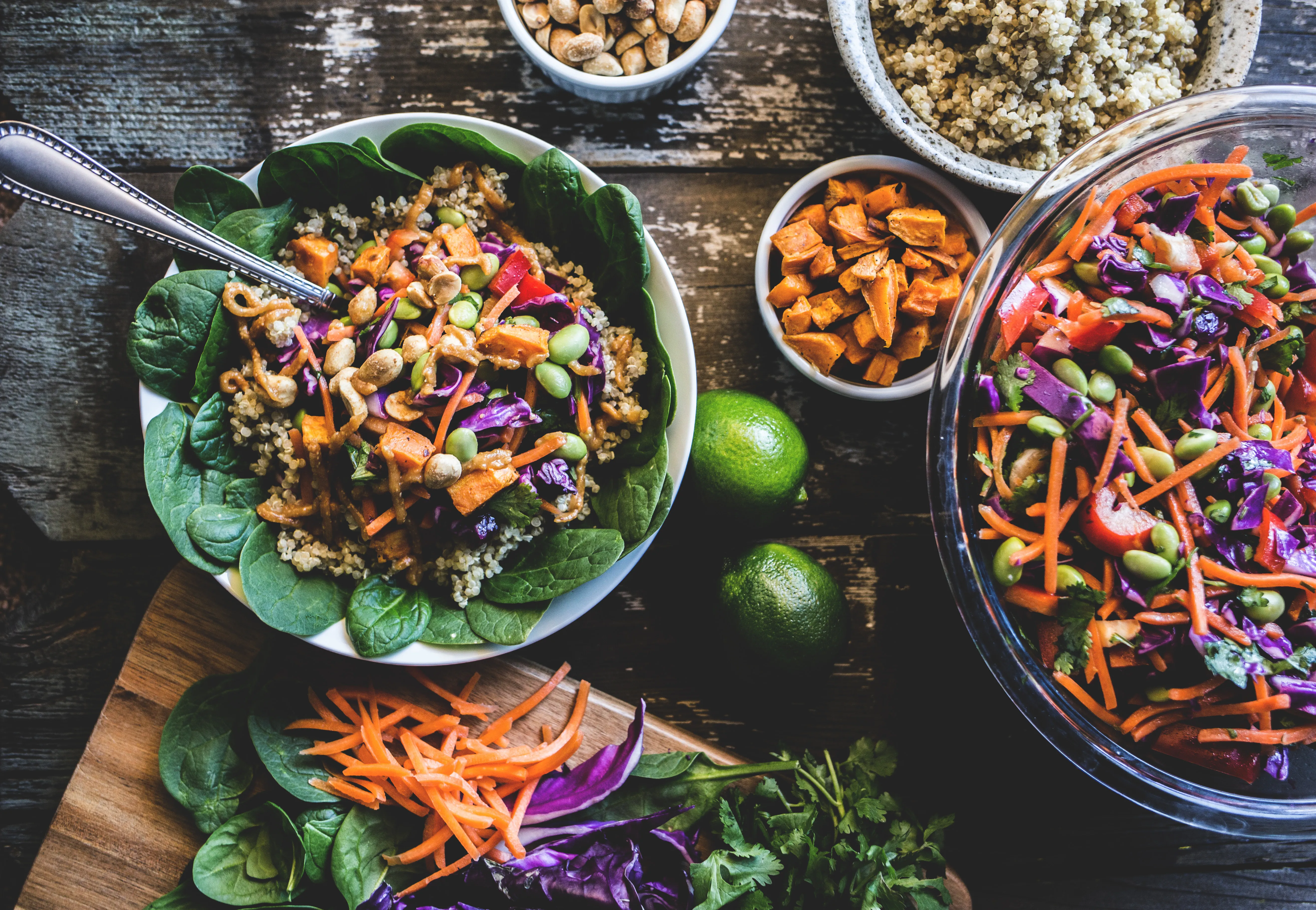 Colourful bowl of quinoa, roasted sweet potato, red cabbage, edamame and peanuts on a bed of spinach
